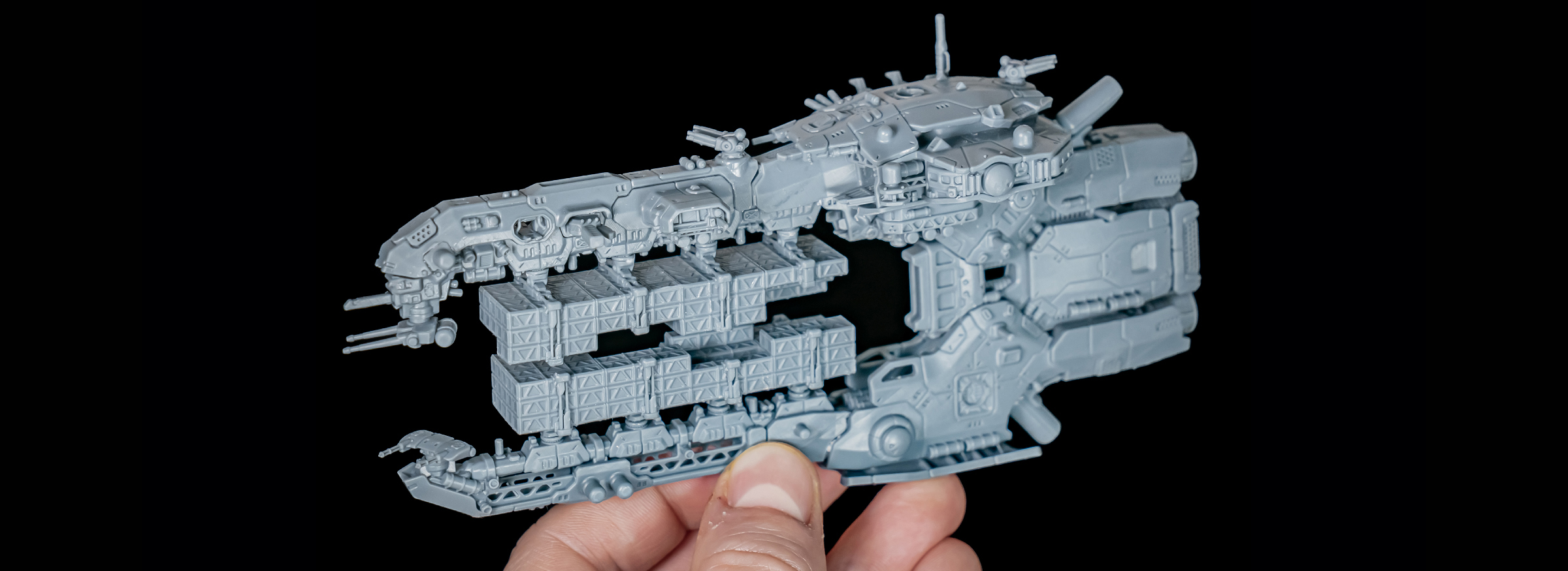 A detailed unpainted Overdrive spaceship miniature held in a hand