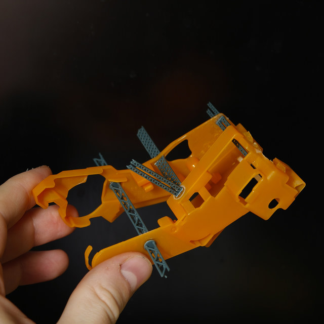 An orange hull with grey structural details held in a hand