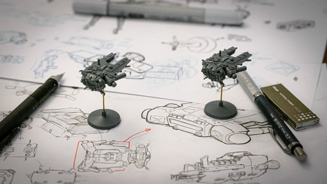 Spaceship miniatures on design sketches at the workbench